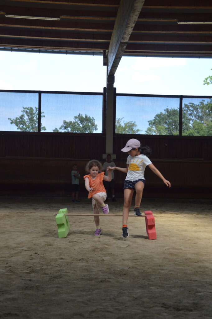 Zwei Kinder springen im Parcours über eine niedrige Stange