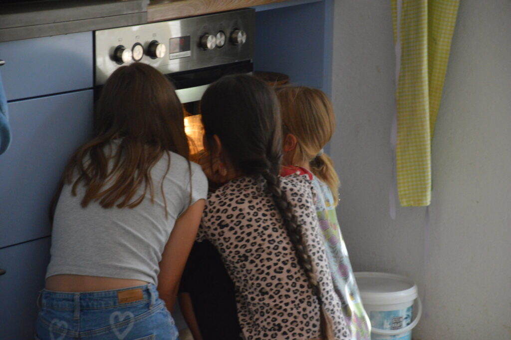 Drei Kinder schauen gespannt in den Backofen