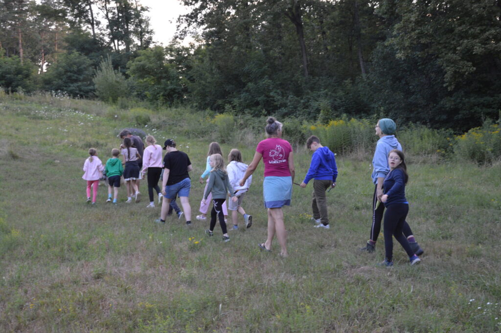 Gruppe von Kindern und Betreuerinnen wandert über eine Wiese