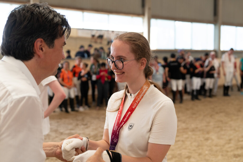 Athletin bekommt bei der Siegerehrung die Medaille überreicht und schüttelt die Hand