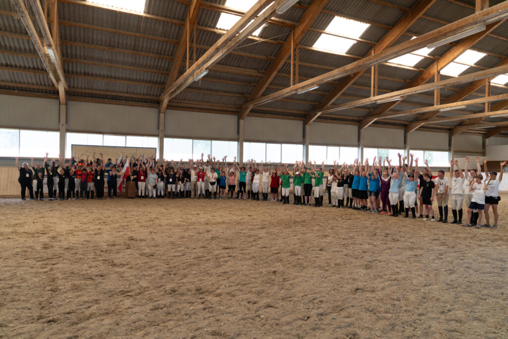 Großes Gruppenfoto aller Teilnehmenden, die jubelnd die Arme in die Luft strecken