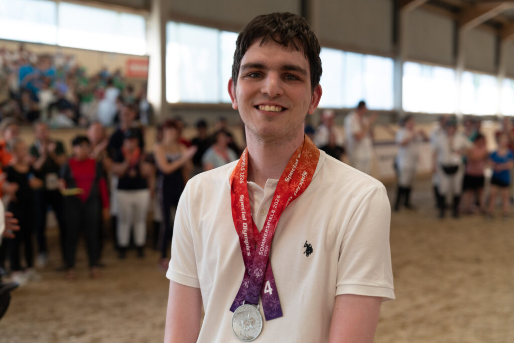 Junger Athlet mit Silbermedaille lächelt in die Kamera