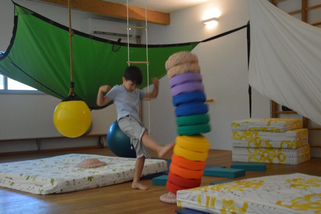 Kind stapelt bunte Ringe im Sensorik-Raum